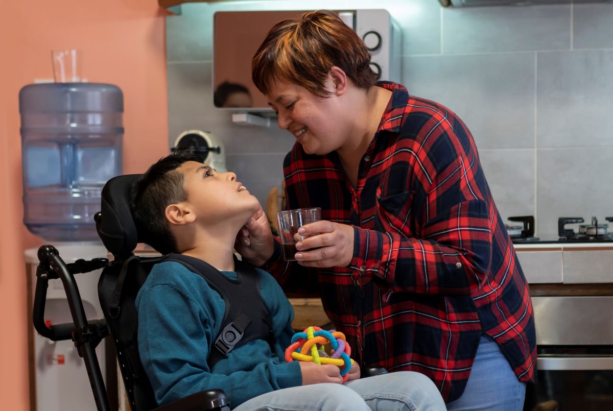 care worker helping boy take a sip of water